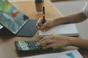 Asian Business woman using calculator and laptop for doing math finance on an office desk, tax, report, accounting, statistics, and analytical research concept photo