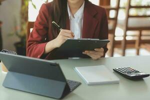 mujer de negocios asiática que usa calculadora y computadora portátil para hacer finanzas matemáticas en un escritorio de oficina, impuestos, informes, contabilidad, estadísticas y concepto de investigación analítica foto