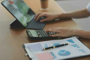 Asian Business woman using calculator and laptop for doing math finance on an office desk, tax, report, accounting, statistics, and analytical research concept photo