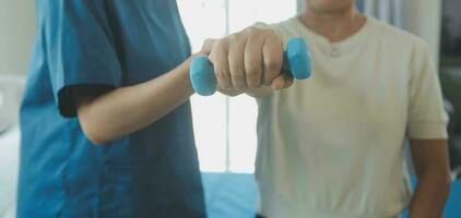 Happy senior woman doing exercise at home with physiotherapist. Old retired lady doing stretching arms at home with the help of a personal trainer during a rehabilitation session. photo