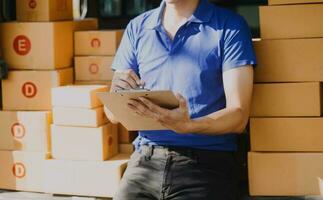 Delivery man with cardboard box checking document list In van and parcels on seat outside the warehouse. photo