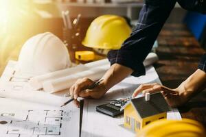 dos especialistas inspeccionar comercial, industrial edificio construcción sitio. real inmuebles proyecto con civil ingeniero, inversor utilizar ordenador portátil. en el antecedentes grua, rascacielos hormigón encofrado marcos foto