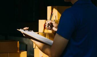 Delivery man with cardboard box checking document list In van and parcels on seat outside the warehouse. photo