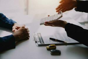 Hand holding car keys and car rental concept A close-up view of the agent, giving the customer the car keys after signing the lease, rental form and car name. photo