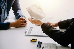 Hand holding car keys and car rental concept A close-up view of the agent, giving the customer the car keys after signing the lease, rental form and car name. photo