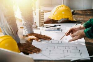Three colleagues discussing data working and tablet, laptop with on on architectural project at construction site at desk in office photo