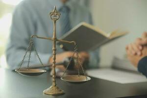 Business and lawyers discussing contract papers with brass scale on desk in office. Law, legal services, advice, justice and law concept picture with film grain effect photo