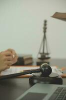 Justice and law concept.Male judge in a courtroom with the gavel, working with, computer and docking keyboard, eyeglasses, on table in morning light photo