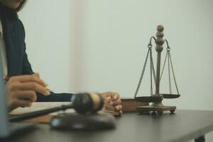 Justice and law concept.Male judge in a courtroom with the gavel, working with, computer and docking keyboard, eyeglasses, on table in morning light photo