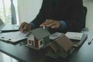 House model with real estate agent and customer discussing for contract to buy house, insurance or loan real estate,real estate concept. photo