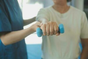 fisioterapeuta hombre dando ejercicio con pesa tratamiento acerca de brazo y hombro de atleta masculino paciente físico terapia concepto foto