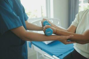 Physiotherapist man giving exercise with dumbbell treatment About Arm and Shoulder of athlete male patient Physical therapy concept photo