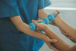 Physiotherapist man giving exercise with dumbbell treatment About Arm and Shoulder of athlete male patient Physical therapy concept photo