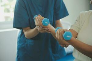 Physiotherapist man giving exercise with dumbbell treatment About Arm and Shoulder of athlete male patient Physical therapy concept photo