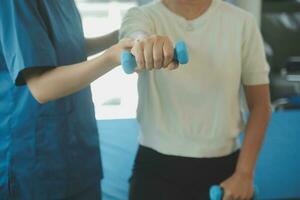 fisioterapeuta hombre dando ejercicio con pesa tratamiento acerca de brazo y hombro de atleta masculino paciente físico terapia concepto foto