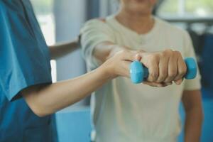 Physiotherapist man giving exercise with dumbbell treatment About Arm and Shoulder of athlete male patient Physical therapy concept photo