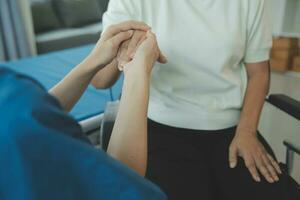 young asian physical therapist working with senior woman on walking with a walker photo