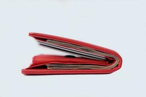 red wallet full of bank notes and credit cards on white background photo