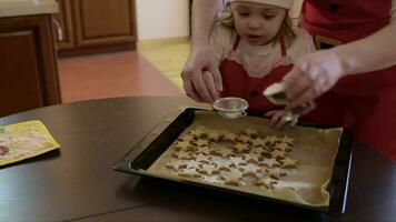Mother with her two years old daughter is spreading sugar powder on Christmas biscuits video