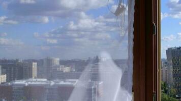 blanco transparente gasa es colgando a amplio ventana decorado por papel mariposas con ciudad ver detrás el cortina video