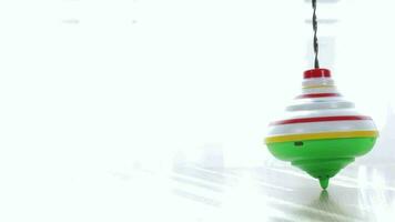 Colorful spinning top moving on a table with transparent curtain on the background. video