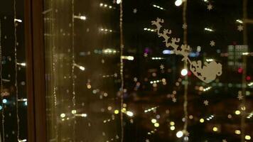 Christmas ornaments and light reflected on the window at night behind transparent curtain video