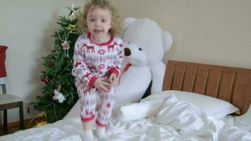 Children dressed in Christmas pajamas are jumping in the bed video
