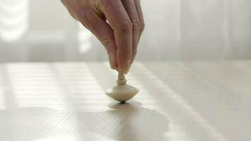 Man hand moving a spinning top on a table. Closeup video