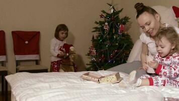 Young mother between 30 and 35 years old shows wooden box with her old photos to her small children video