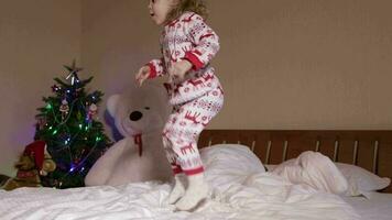 Children dressed in Christmas pajamas are jumping in the bed video