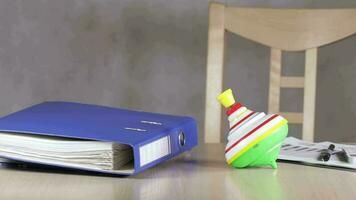 Colorful spinning top beside a document binder and a chart diagram paper on the table. video