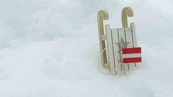 Wooden made mini sleighs and Austrian flag in the snow. Free space for a text. Dynamic zoom video