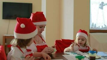 Jeune mère entre 25 et 30 ans vieux est La peinture avec sa les enfants à rond table dans vivant chambre. Noël période vacances video