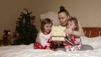 Young mother shows wooden box to her small children in the bed video