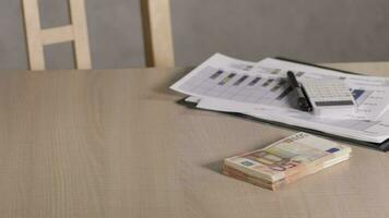 Pile of banknotes of 50 euros on a table with diagram and calculator. video