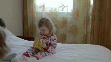 Children dressed in Christmas pajamas open gift box on christmas day video