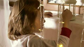 Little boy in christmas pajamas decorating the window with christmas ornaments and christmas light video