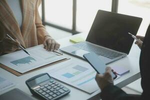 Asian Business woman using calculator and laptop for doing math finance on an office desk, tax, report, accounting, statistics, and analytical research concept photo
