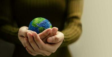 World Earth Day Concept. Green Energy, ESG, Renewable and Sustainable Resources. Environmental and Ecology Care. Woman Hand Embracing a Green Globe, Front View photo