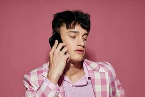 foto de romántico joven novio con un teléfono en mano rosado chaqueta de sport Moda elegante estilo estilo de vida inalterado