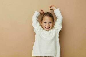 Portrait of happy smiling child girl in white sweater posing hand gestures Lifestyle unaltered photo