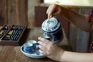 A photo corner that simulates the tea culture of the Chinese people. with Asian women playing Chinese roles Use your hand to pour tea into a teacup with a dragon pattern, which is a popular pattern.