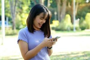 Asian woman happy face using phone looking at social media, playing online games, shopping online, load applications. Soft and selective focus. photo