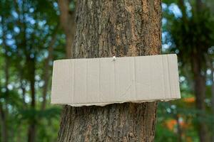 Crate paper sign on the tree for writing environmental campaign messages and forest conservation, for example, do not cut trees, plant conservation areas, love the world, love trees, etc. photo