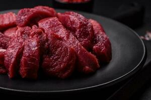 Juicy raw beef with spices, salt and herbs on a dark concrete background photo