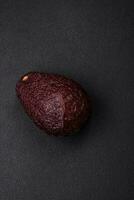 Fresh, ripe, soft brown colored avocado on a dark concrete background photo