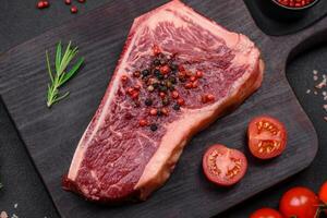 Fresh juicy raw new york beef steak with salt, spices and herbs photo