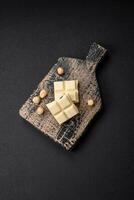 Delicious sweet white chocolate broken into cubes on a wooden cutting board photo