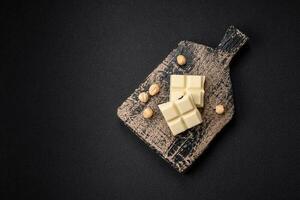 Delicious sweet white chocolate broken into cubes on a wooden cutting board photo