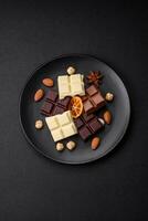 A mix of several types of delicious sweet chocolate broken into cubes on a black plate photo